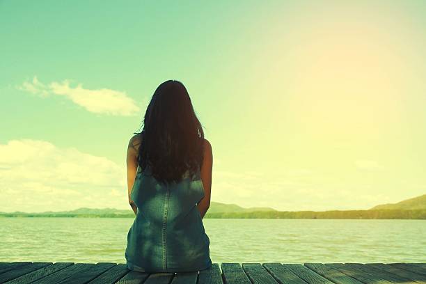 istock woman sit alone at the edge of bridge 627499590