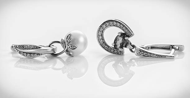 Closeup jewelry sets of studded silver earrings and pendants on acrylic surface on grey  background.