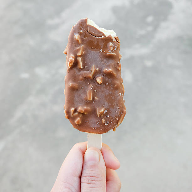 istock Hands holding vanilla icecreams covered with chocolate and almon 627503360