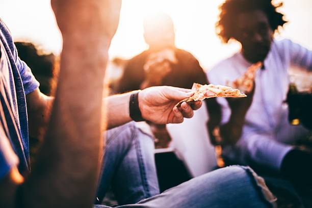 Friends eating pizza in sunset