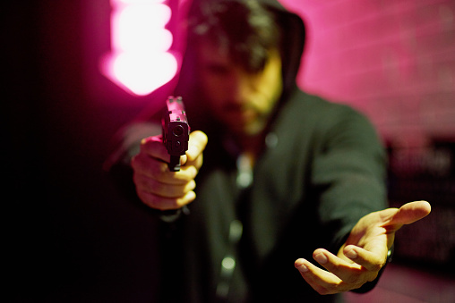 Portrait of a gun-wielding thief aiming his weapon