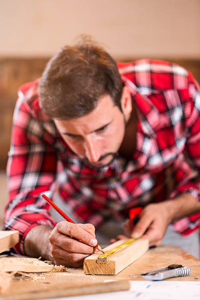 Adult carpenter measuring a plank