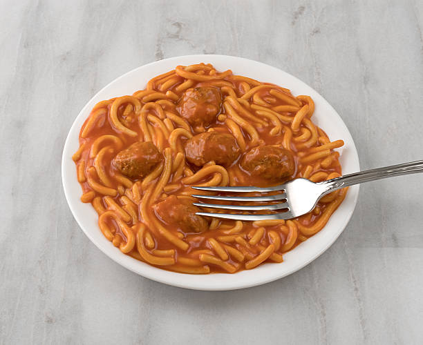 Plate of spaghetti and meatballs with fork on marble