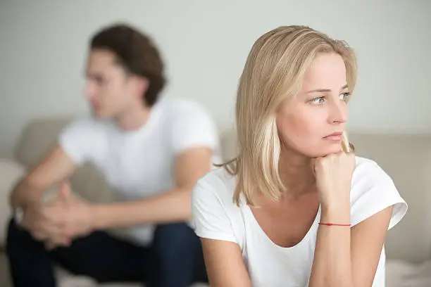 Photo of Sad woman thinking over a problem, man sitting aside