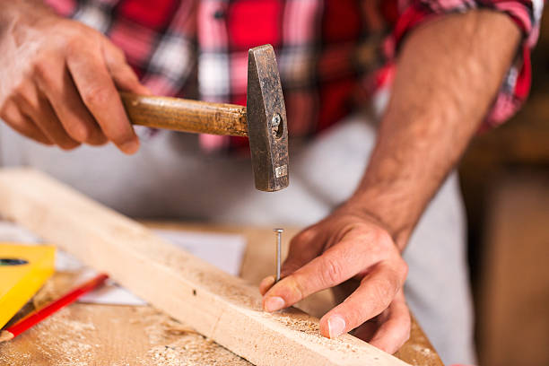 istock Hammering a nail into wooden board. Close up 627557564