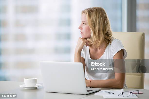 Mujer Yong Con Portátil Mirando A La Ventana Foto de stock y más banco de imágenes de Oficina - Oficina, Tristeza, Ejecutiva
