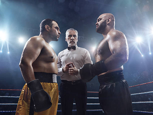 Boxing: Face to face A picture of two boxers face to face. Referee stands between them. The sportsmen are on boxing ring with bleachers full of people boxing referee stock pictures, royalty-free photos & images