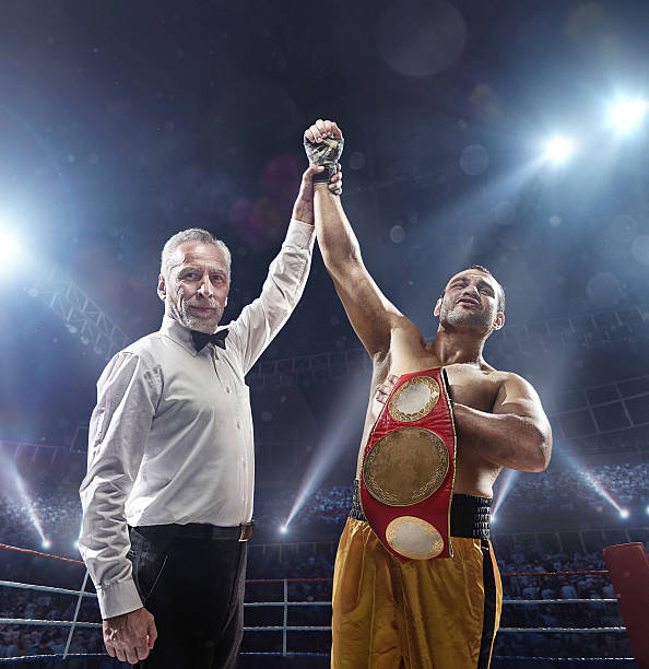 Boxing: Winner boxer A picture of a winner boxer. Referee put his arm in the air.  Sportsman is on boxing ring with bleachers full of people boxing referee stock pictures, royalty-free photos & images