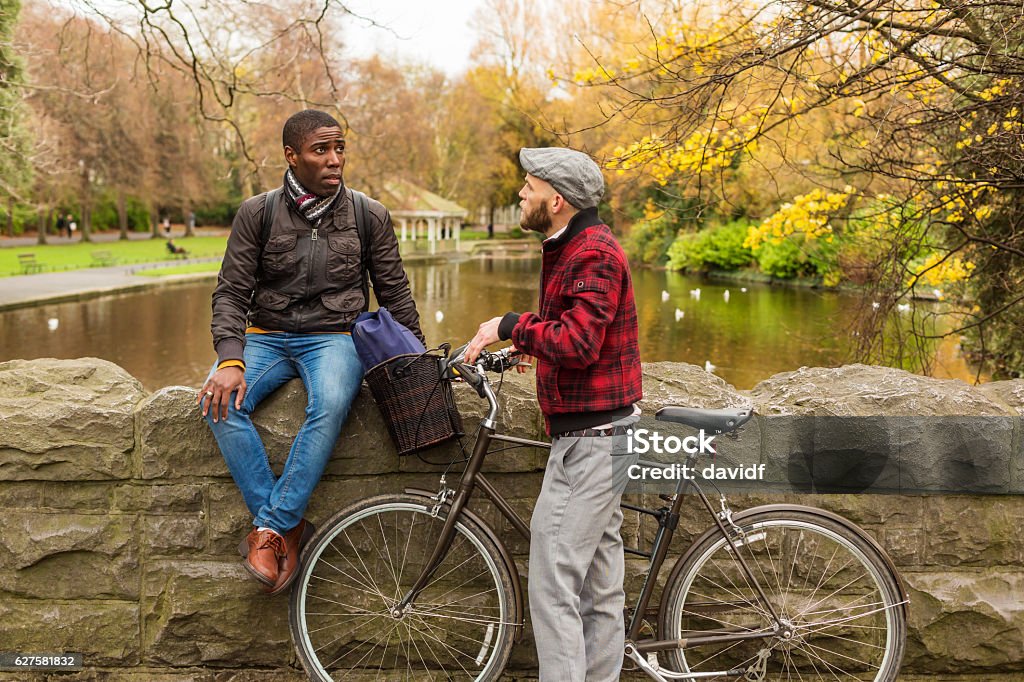 Happy Gay Men Meeting in a Park Happy gay men couple meeting in a park with a bicycle Dublin - Republic of Ireland Stock Photo