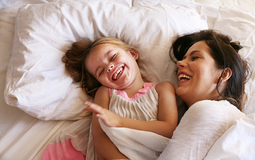 Mother with her daughter enjoy in bed at the morning. Space for copy.