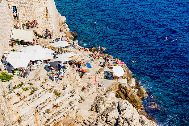 Dubrovnik, Croatia - September 22, 2016: This is a rocky seafront area outside the fortress wall of Dubrovnik where tourists come to swim and sunbath