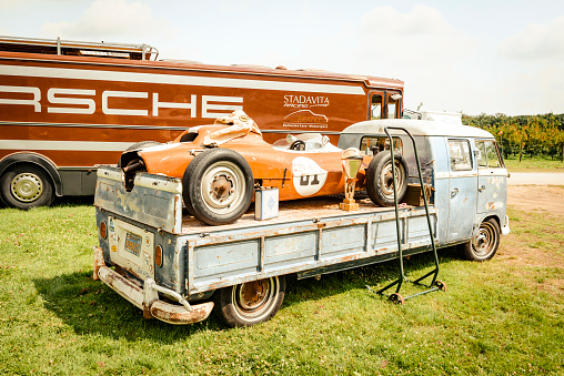 Jüchen, Germany - August 5, 2016: Porsche Formula racing car on a Transporter 1960s Volkswagen Bus flatbed pick up double cab with beautiful patina. There is a Porsche racing truck parked in the background. The car is on display during the 2016 Classic Days at castle Dyck.