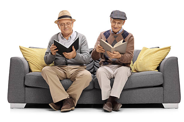 istock Seniors sitting on a sofa and reading books 627586410