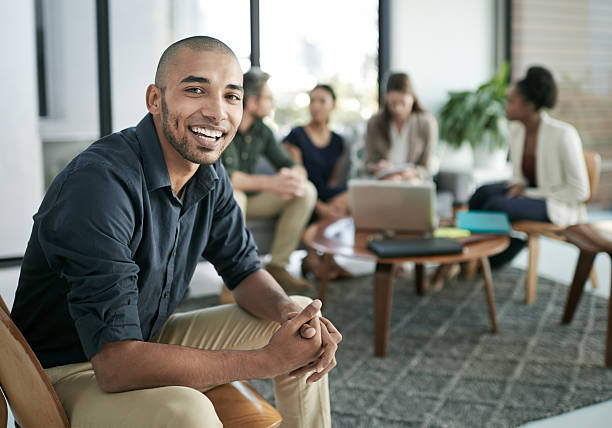 We're all in it together Portrait of a young businessman with his team having a meeting in the background casual clothing stock pictures, royalty-free photos & images