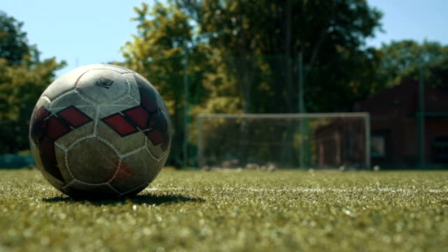 Soccer player kicking ball on field, close up