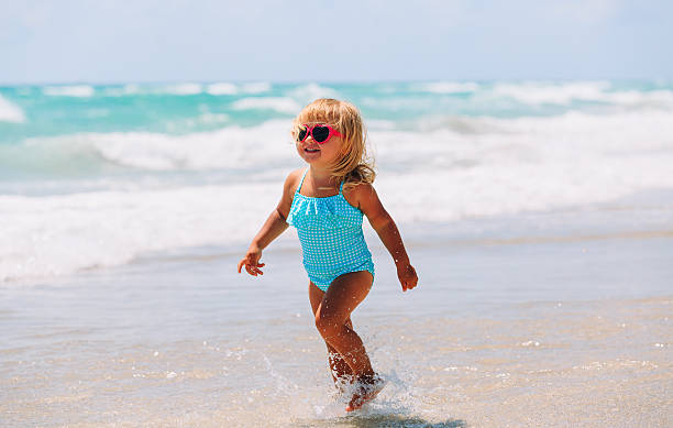 istock little girl run play with waves on the beach 627626882