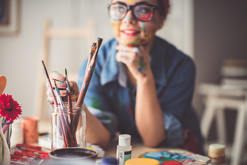 Young woman thinking of perfect paintbrush