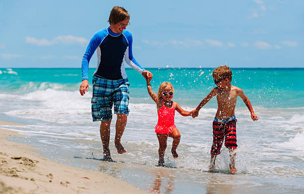 istock father with little son and daughter run at beach 627627456