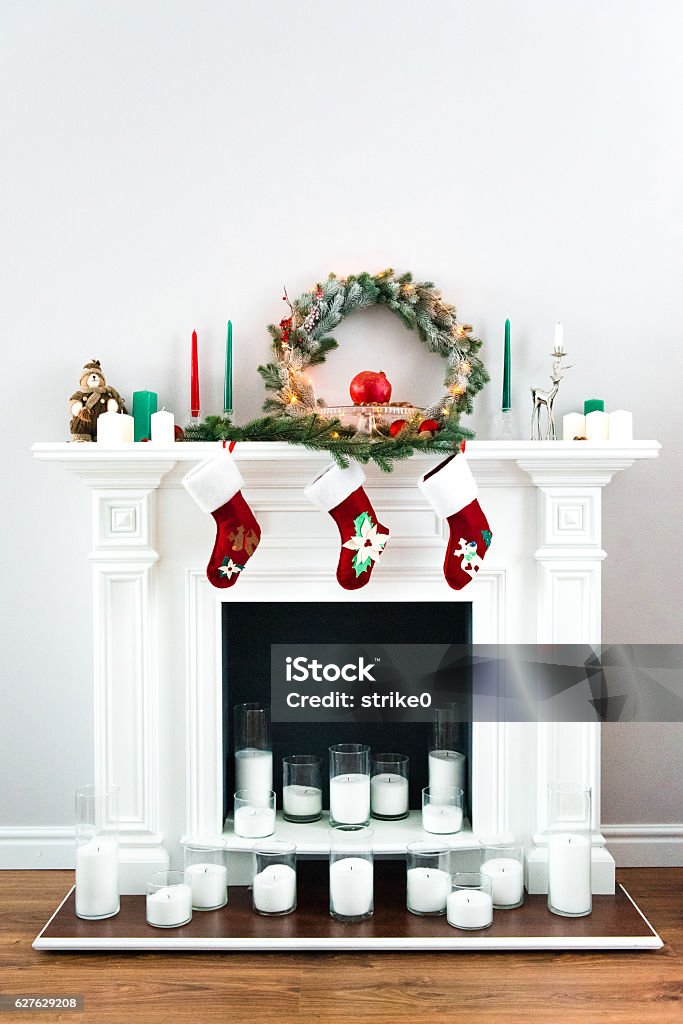 great white fireplace decorated with many candles A picture of a great white fireplace decorated with many candles, green pine wreaths and bright red Christmas socks. Christmas Stock Photo