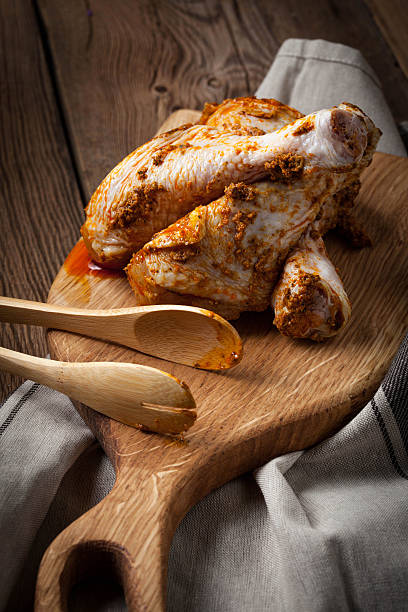 istock Marinated chicken drumsticks on a wooden chopping board. 627646446
