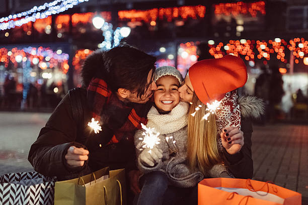 Young family celebrating Christmas Cute couple with sparklers wishing Happy new Year to the little daughter december stock pictures, royalty-free photos & images