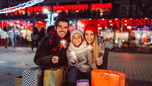 Young family spending Christmas together Cute couple with sparklers celebrating Christmas in the city three way kiss stock pictures, royalty-free photos & images