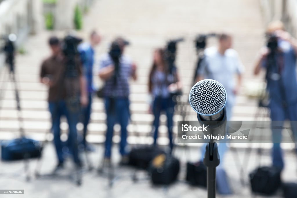 News conference Microphone in focus against blurred camera operators and journalists. Press conference. Journalist Stock Photo
