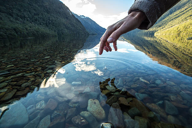 istock Finger touches surface of mountain lake 627676416