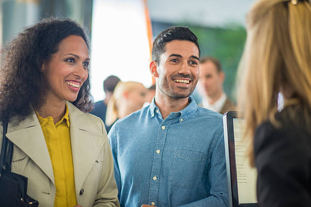 Customers in bank Customers talking and smiling with bank teller at bank counter. bank teller stock pictures, royalty-free photos & images