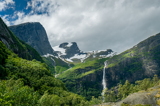 Beautiful green mountain slopes and waterfalls on the hiking path to Briksdalsbreen glacier viewpoint. Briksdal, Norway.