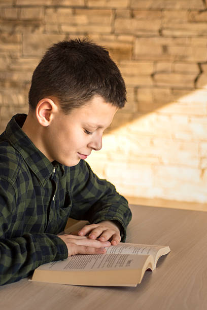 istock Young Boy Reading Book and Studying on Table at Home 627681734