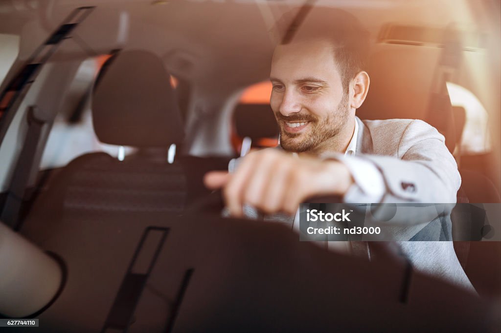 Handsome businessman driving car Handsome businessman driving car before buying Car Stock Photo