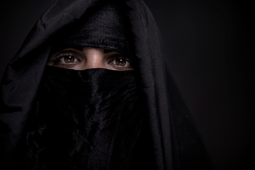 An Asian woman, wearing a niqab, stares confidently into the camera
