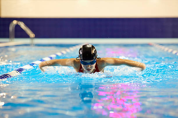 chica nadadora adolescente en la piscina nada mariposa en el interior. - butterfly swimmer fotografías e imágenes de stock