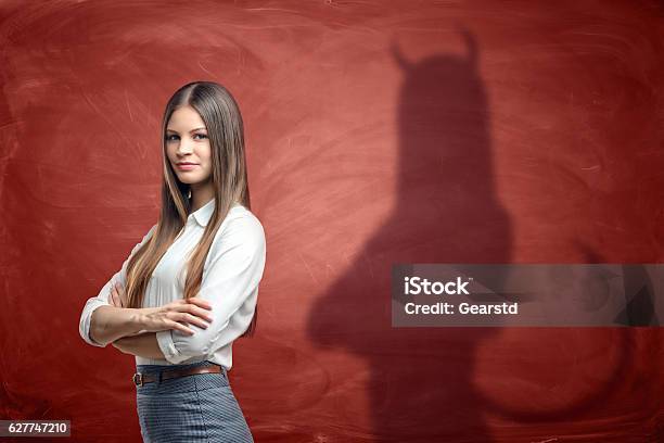 Young Businesswoman Is Casting Shadow Of Devil On Rusty Orange Stock Photo - Download Image Now