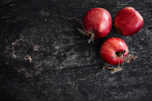 Red apples on a dark wooden surface.