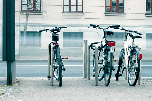 Three parked and locked bicycles in a city street.