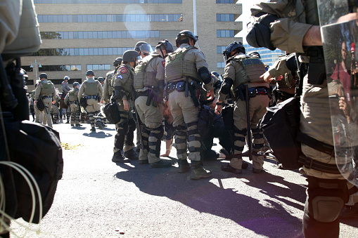 Austin, Texas, USA - November 19, 2016: Texas Department of Public Safety troopers in full riot gear arrest a counter-demonstrator for trying to break through police lines at a 'White Lives Matter' demonstration just south of the Capitol grounds. The 'White Lives Matter' demonstrators, numbering about 20 people at the most, came from Houston with the message that the federal hate crime law is unfair to white people.