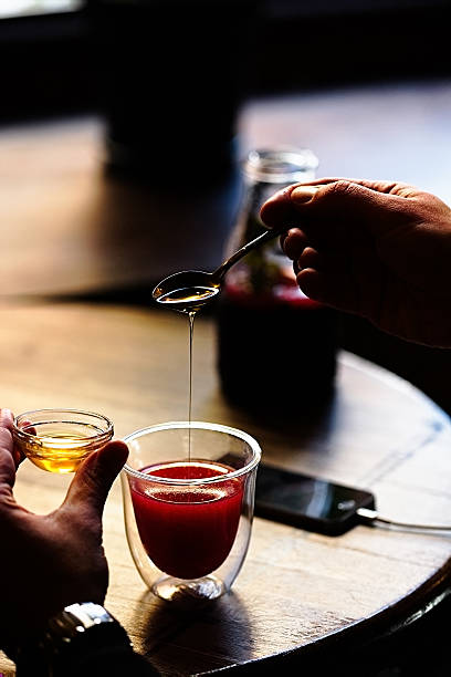 istock Spoon with pouring honey in man's hands 627771248