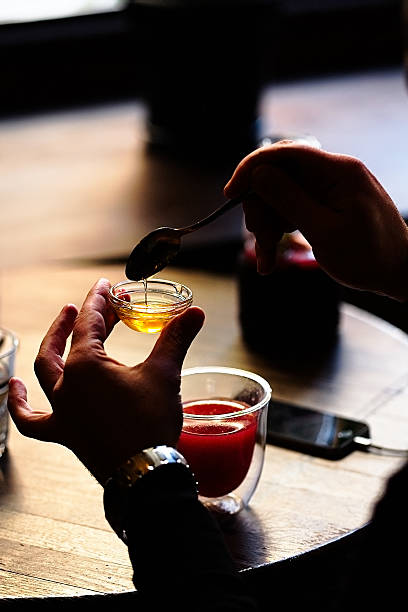 istock Spoon with pouring honey in man's hands 627771270