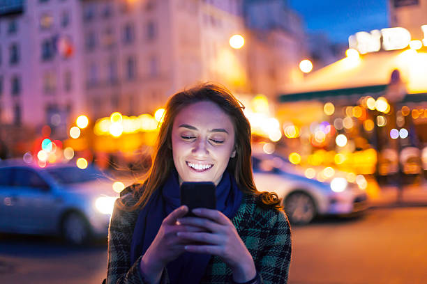 istock Smiling woman using smart phone on street by night 627771680