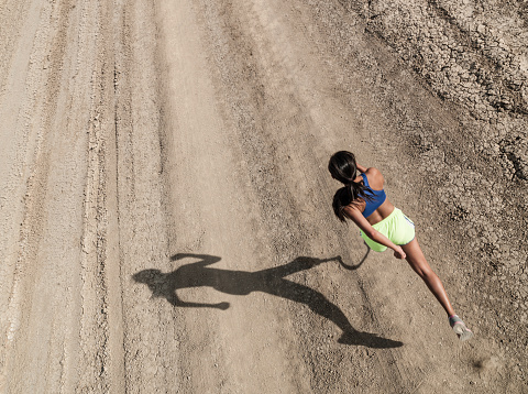 Asian Women With Prosthetic Leg Running In The Desert.  You can only see the prosthetic leg in the shadow of the runner.