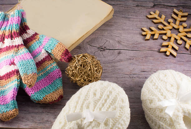 book, snowflake, knitted socks and mittenson wooden background