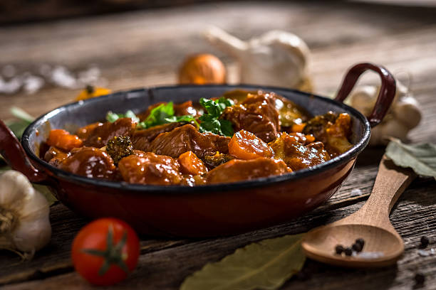 Meat stewed with vegetable on rustic wooden background Meat stewed with vegetable on rustic wooden background beef stew stock pictures, royalty-free photos & images