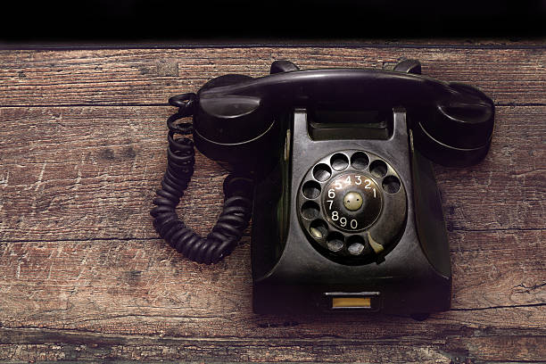 istock vintage black rotary phone with dust and scratches on table 627806374