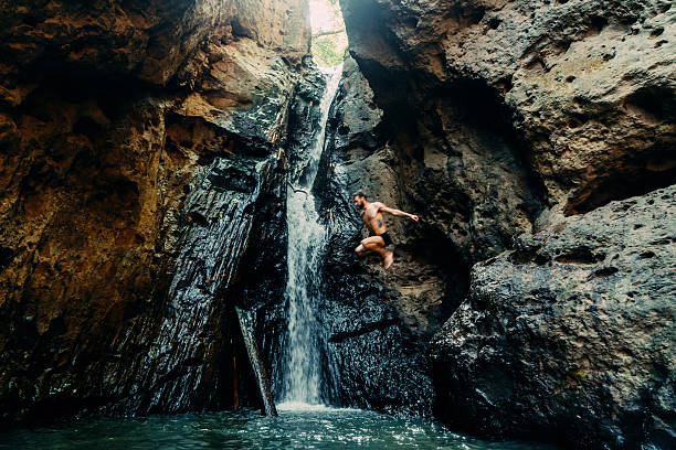 hombre saltando a cascada tropical - waterfall thailand tropical rainforest tropical climate fotografías e imágenes de stock