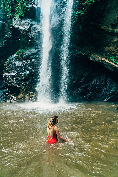 istock Woman swimming in tropical waterfall 627814896