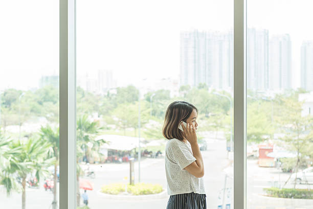istock Woman talking on cellphone with the building window backgound 627814934