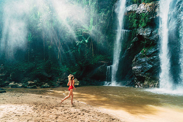 Woman running to tropical waterfall