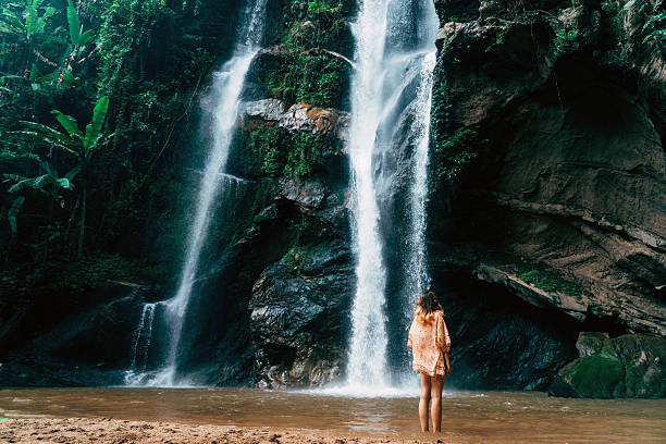 istock Woman looking at tropical waterfall 627815034